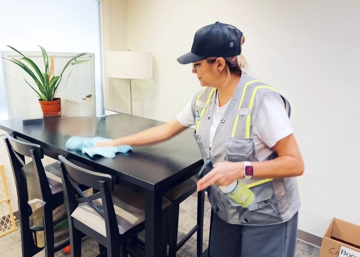 Office cleaner wipes down table in office kitchenette