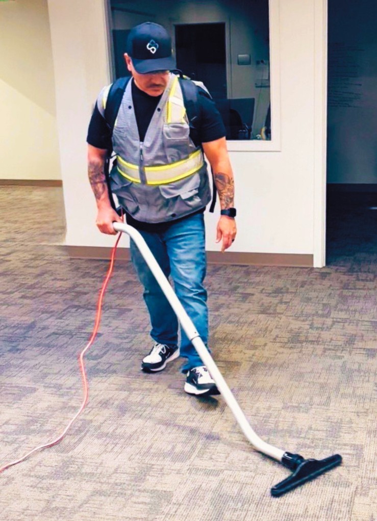 Office cleaner vacuums carpet with commercial vacuum cleaner