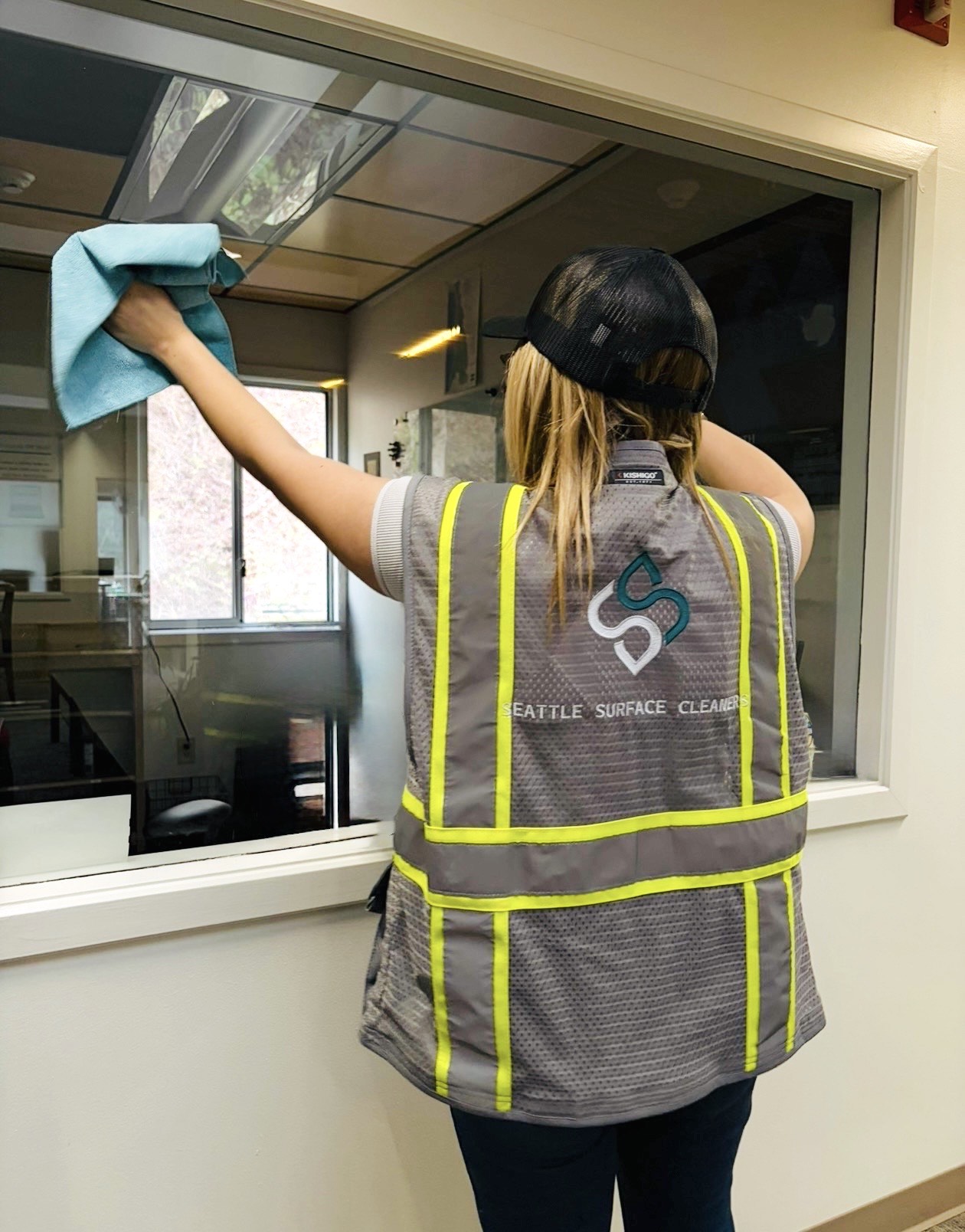Office cleaner cleans an interior office window